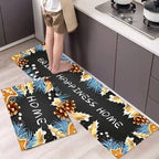 Two decorative kitchen mats with floral designs and text on a kitchen floor.