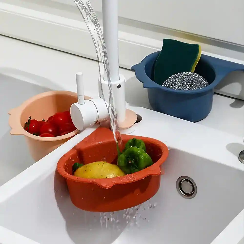 Vegetables being washed in a red basin under running water in a kitchen sink.
