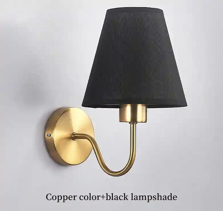 Wall-mounted lamp with black shade and gold arm on a light gray background