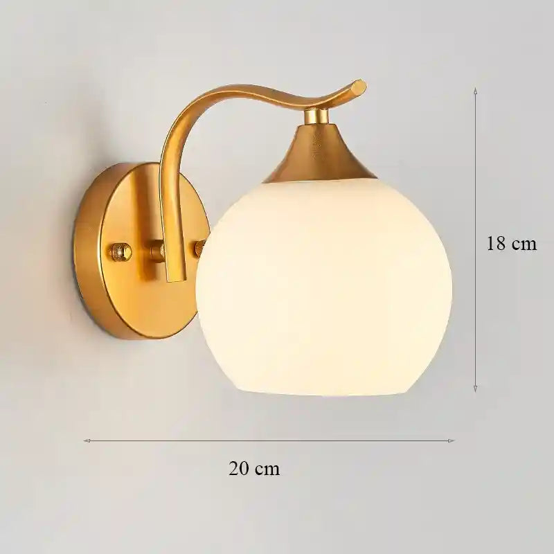 Wall-mounted lamp with gold fixture and white glass shade, shown on a light gray background.