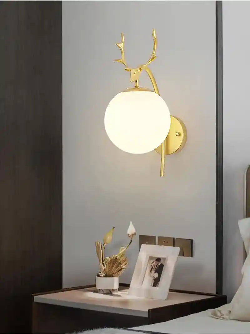 Wall-mounted light fixture with deer antlers on a wall in a room setting.