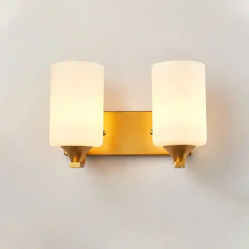 Wall-mounted light fixture with gold frame and white glass on a plain wall.