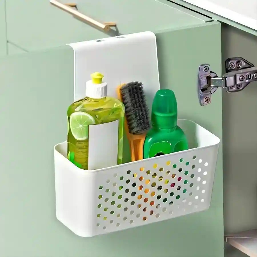 White perforated storage basket attached to a cabinet door, holding cleaning supplies.