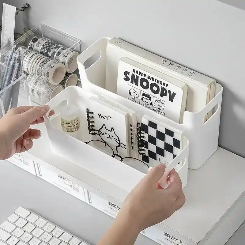 White storage bin with compartments holding stationery items on a desk.