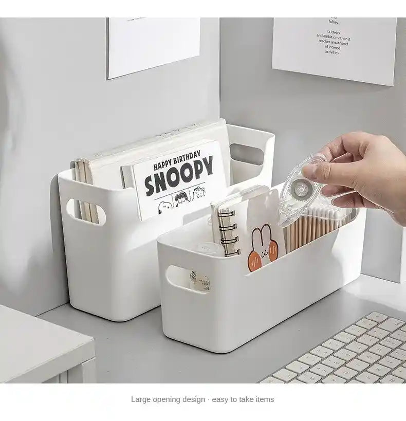 White storage bins with office supplies on a desk, featuring a 'Happy Birthday Snoopy' magazine.