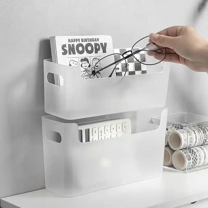 White storage box with compartments on a white surface, containing items like glasses and a birthday card.
