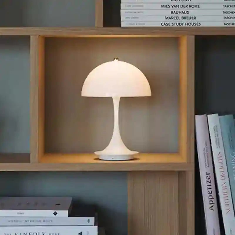 White table lamp on a wooden shelf with books in the background