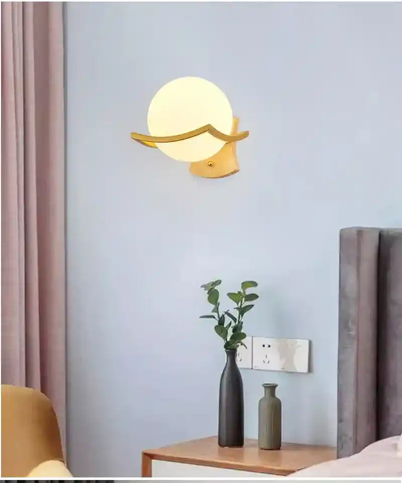 Wall-mounted lamp with a round glass shade on a light blue wall.
